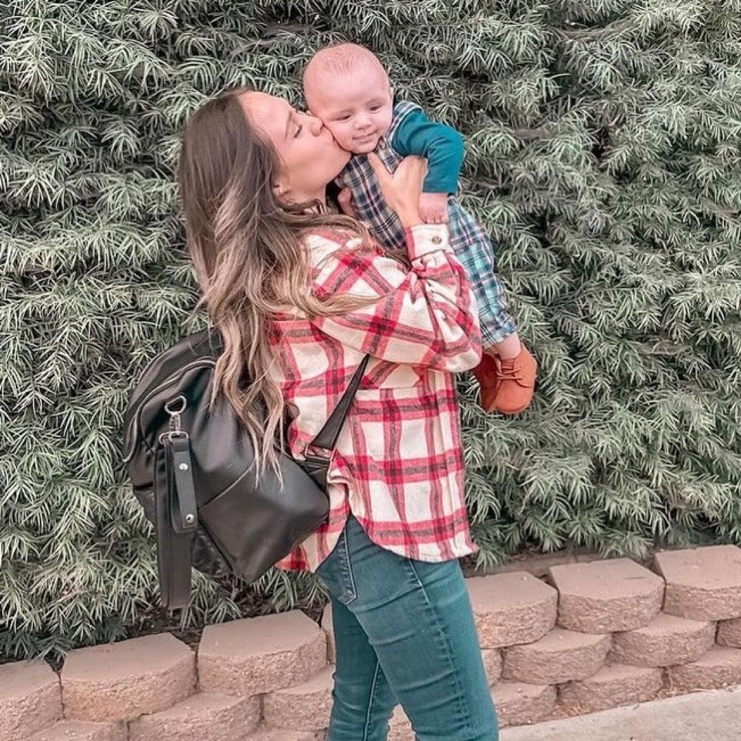 Mom and baby cuddling with a hands free diaper bag in black